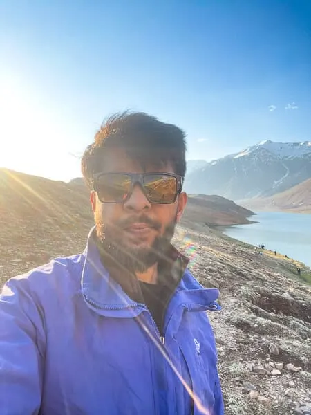 Ayush, founder of The Lazy and Slow, beside a mountain lake